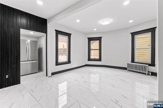 spare room featuring marble finish floor, radiator heating unit, baseboards, and recessed lighting