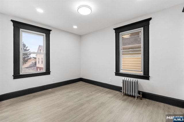 unfurnished room with radiator heating unit, recessed lighting, light wood-style flooring, and baseboards