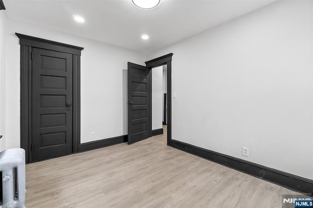 unfurnished room featuring recessed lighting, radiator, light wood-style flooring, and baseboards