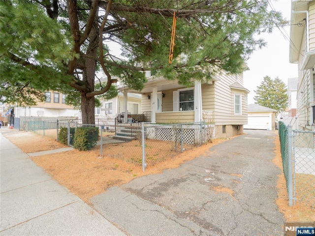 view of front of home with a fenced front yard, a porch, a gate, a garage, and an outdoor structure