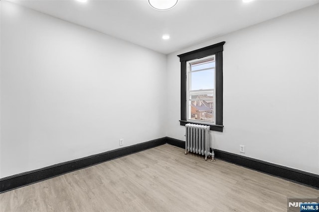 unfurnished room featuring radiator heating unit, recessed lighting, wood finished floors, and baseboards