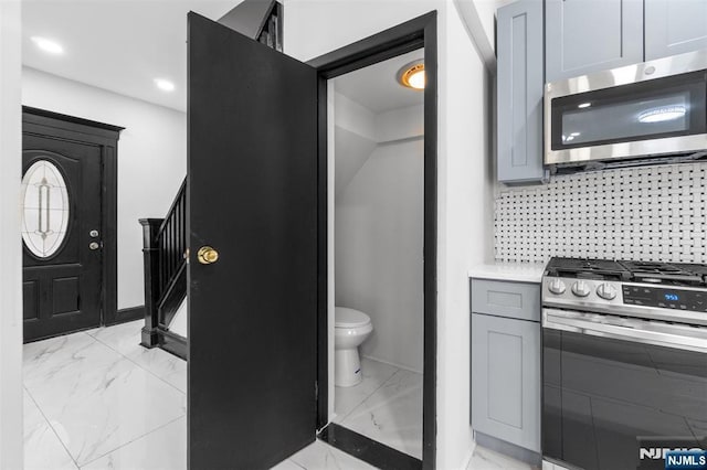 bathroom with tasteful backsplash, marble finish floor, and toilet