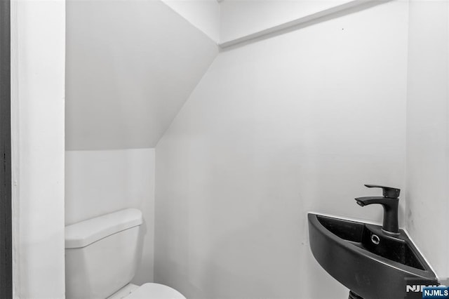 half bath featuring vaulted ceiling and toilet