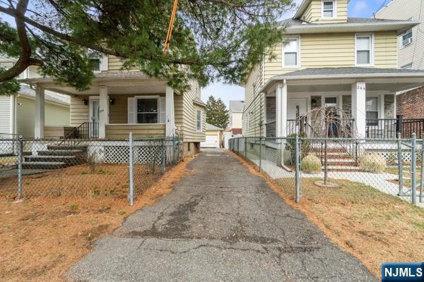 view of front of home with a garage, a fenced front yard, and a porch