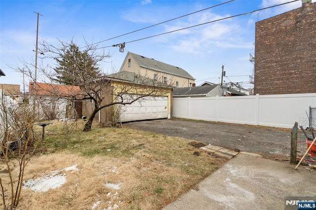 view of yard featuring driveway, a garage, and fence