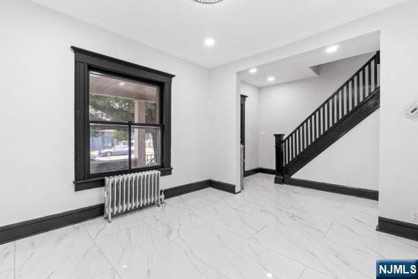 foyer entrance with radiator, baseboards, and stairs