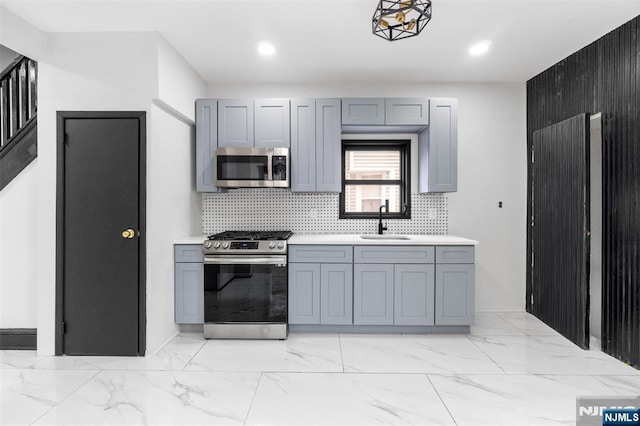 kitchen featuring appliances with stainless steel finishes, marble finish floor, a sink, and gray cabinetry