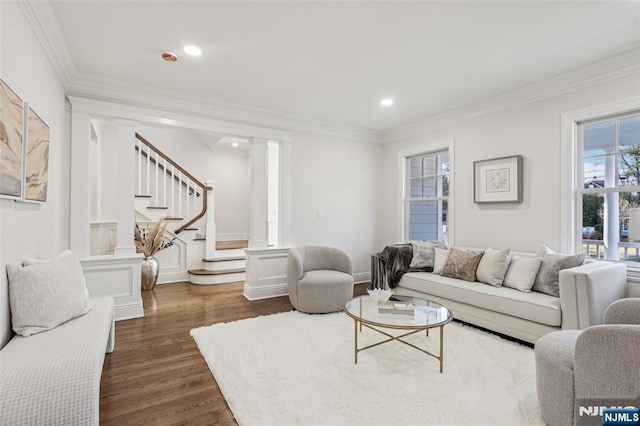 living room featuring decorative columns, ornamental molding, dark wood finished floors, and stairway