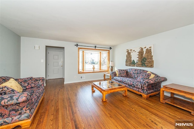 living area with wood finished floors, visible vents, and baseboards