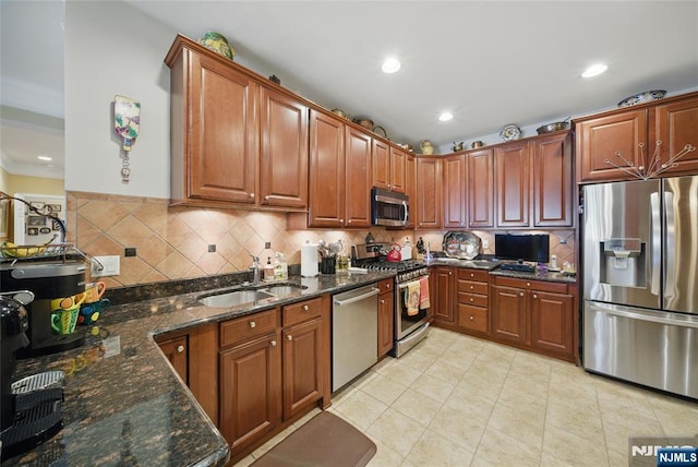 kitchen featuring appliances with stainless steel finishes, backsplash, dark stone countertops, and a sink