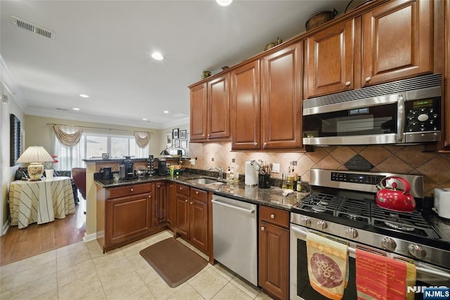 kitchen with crown molding, visible vents, appliances with stainless steel finishes, a sink, and a peninsula