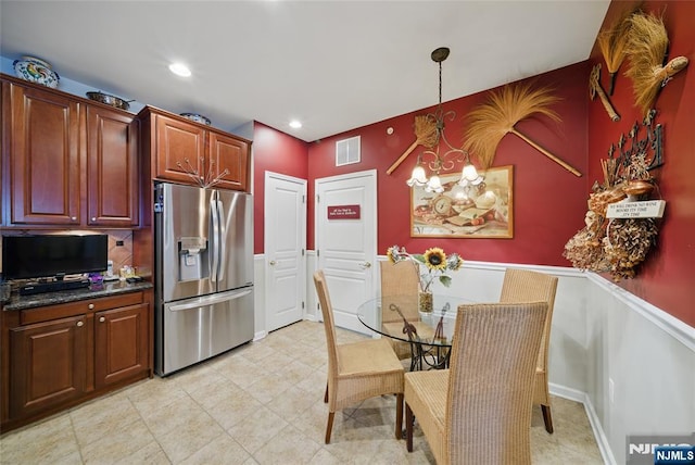 kitchen featuring a chandelier, visible vents, dark countertops, stainless steel fridge, and decorative light fixtures