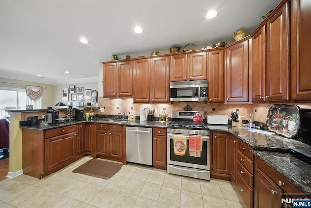 kitchen featuring a peninsula, a sink, stainless steel appliances, crown molding, and backsplash