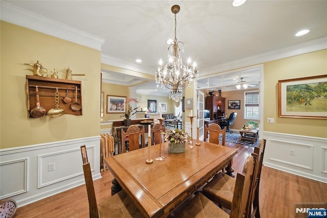 dining area featuring a wainscoted wall, decorative columns, ornamental molding, and wood finished floors