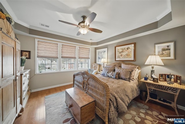 bedroom with baseboards, visible vents, a ceiling fan, ornamental molding, and wood finished floors