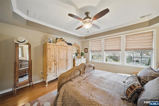 bedroom with crown molding, visible vents, and wood finished floors