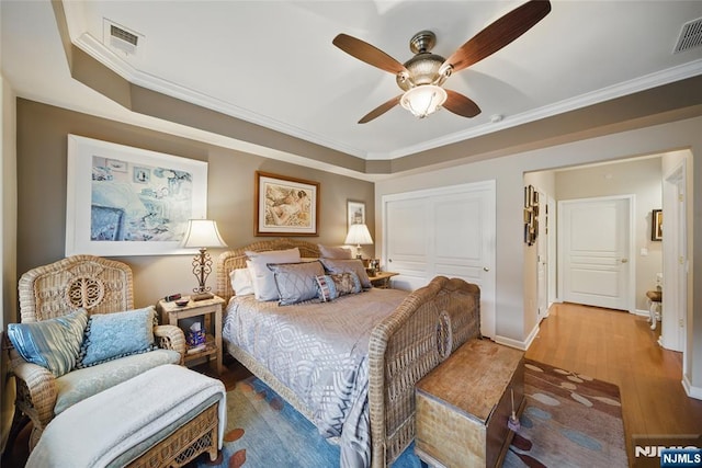 bedroom featuring a closet, visible vents, crown molding, and wood finished floors