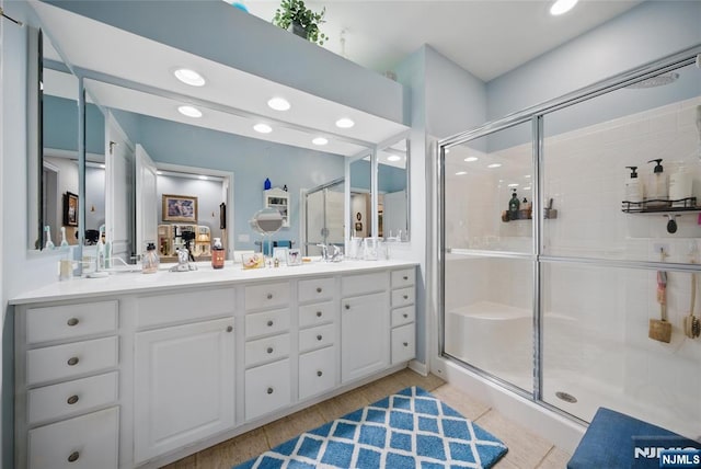 bathroom with a sink, double vanity, a shower stall, and recessed lighting