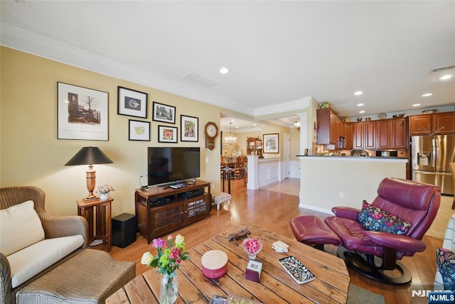 living room with ornamental molding, an inviting chandelier, recessed lighting, and light wood-style floors