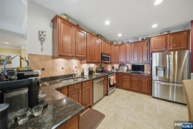 kitchen featuring recessed lighting, a sink, appliances with stainless steel finishes, tasteful backsplash, and dark stone countertops