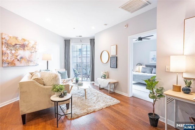 sitting room featuring a ceiling fan, visible vents, baseboards, and wood finished floors