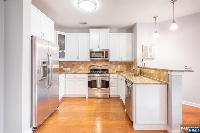 kitchen featuring appliances with stainless steel finishes, light wood-type flooring, a sink, and visible vents