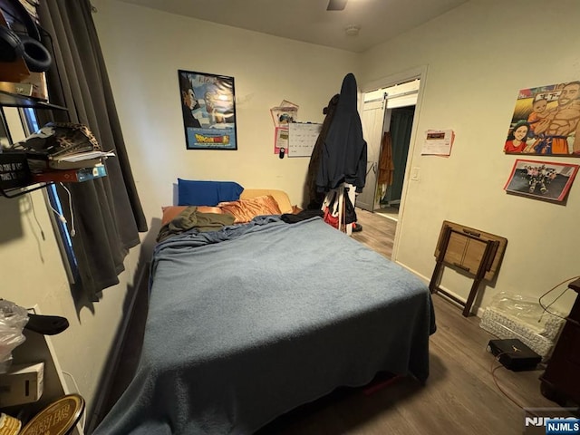 bedroom featuring a ceiling fan, wood finished floors, and a barn door