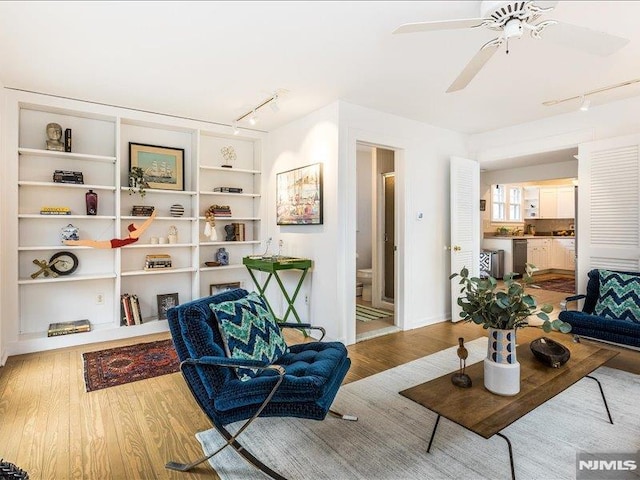 living area with wood finished floors, a ceiling fan, and track lighting