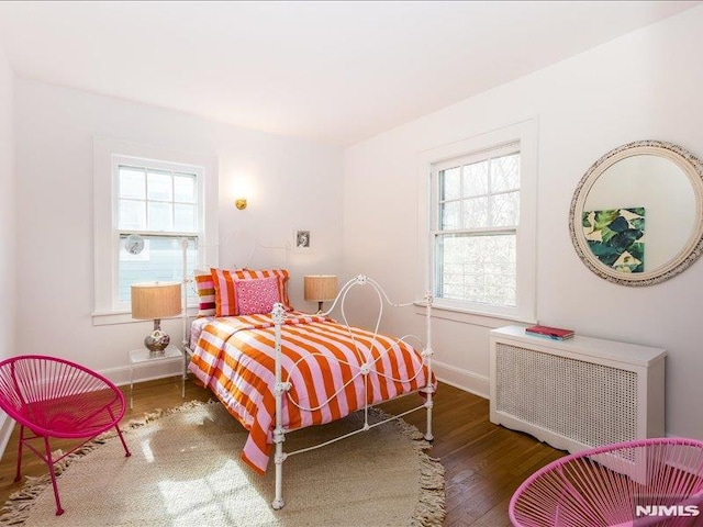 bedroom featuring radiator heating unit, baseboards, and wood finished floors