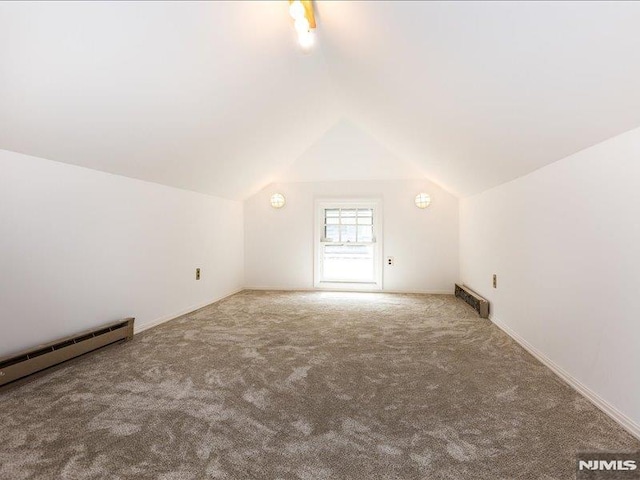 additional living space with vaulted ceiling, a baseboard heating unit, and carpet floors