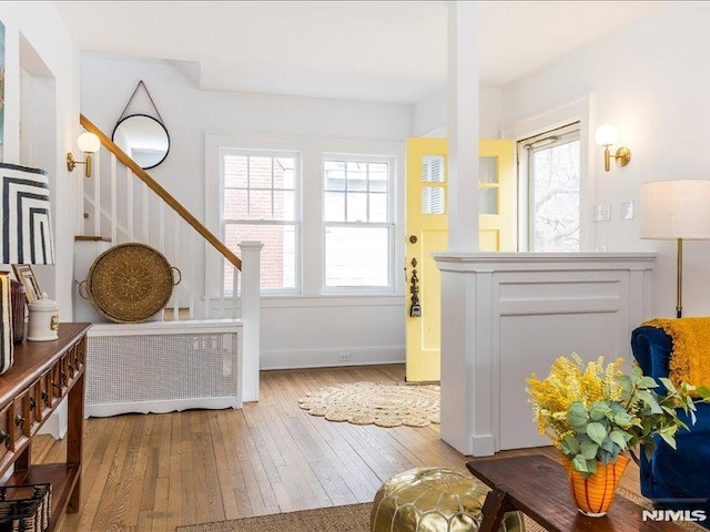 interior space with radiator, baseboards, stairway, and hardwood / wood-style floors