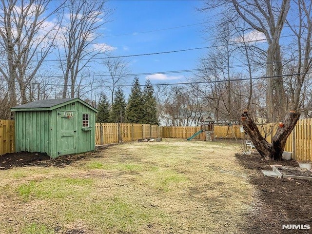 view of yard with a storage shed, a fenced backyard, a playground, and an outdoor structure