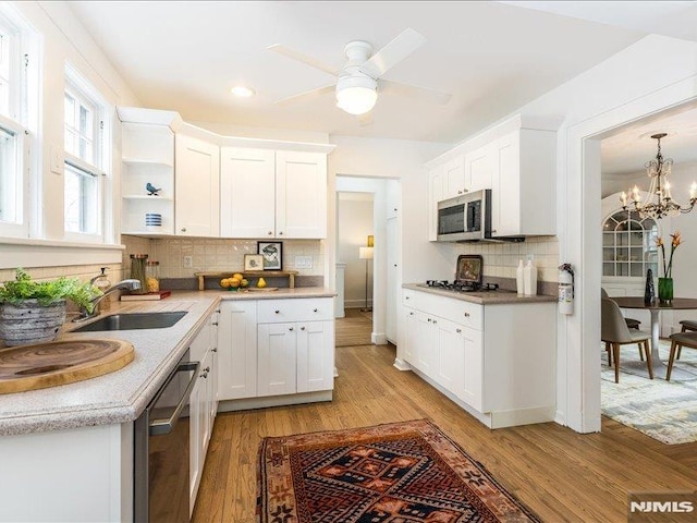 kitchen featuring light countertops, appliances with stainless steel finishes, white cabinetry, a sink, and light wood-type flooring