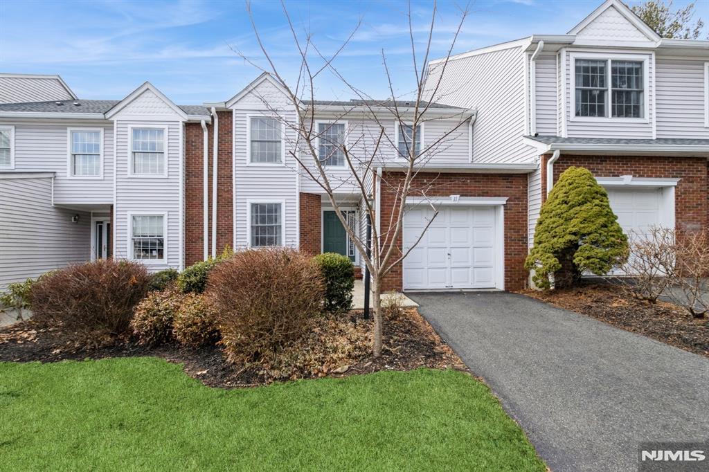 view of property with a front lawn, aphalt driveway, and brick siding