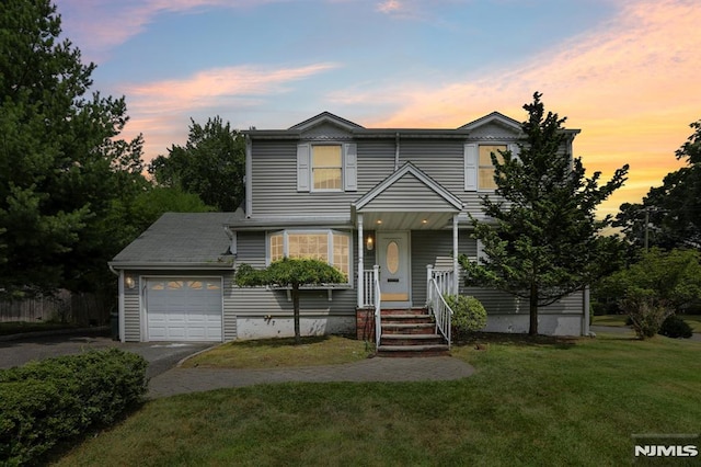 view of front facade featuring a lawn, an attached garage, and driveway