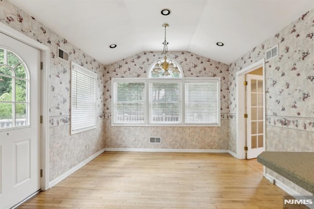 unfurnished dining area featuring visible vents, wallpapered walls, and vaulted ceiling