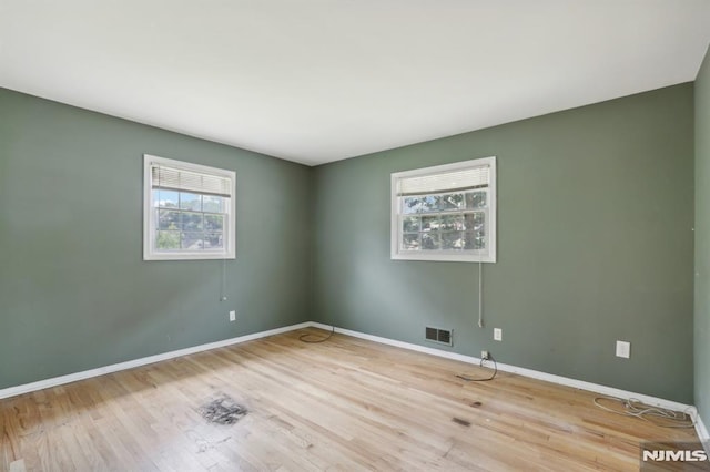 unfurnished room with visible vents, baseboards, and wood finished floors