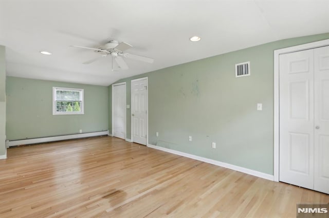 unfurnished bedroom with multiple closets, wood finished floors, baseboards, and a baseboard radiator