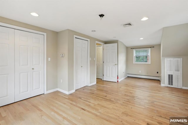 unfurnished bedroom with visible vents, multiple closets, light wood finished floors, baseboards, and baseboard heating