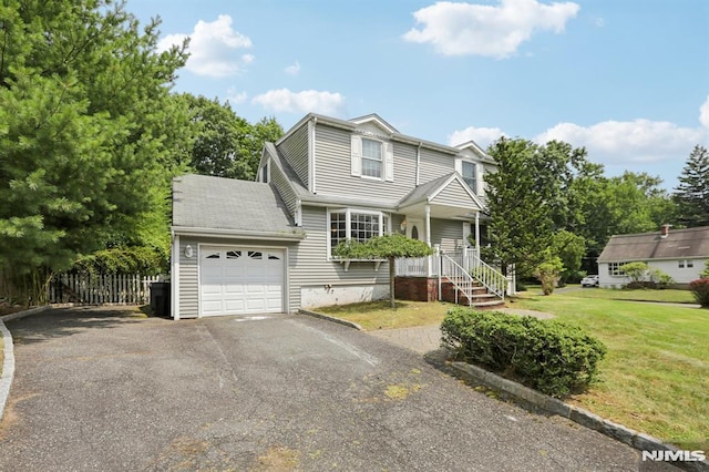 view of front of property featuring a garage, driveway, a front lawn, and fence