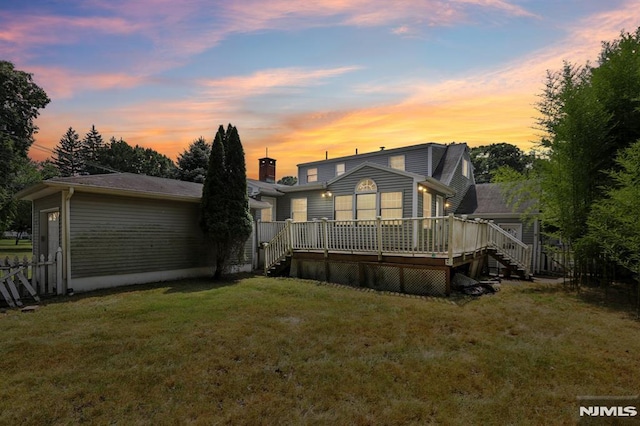 back of property featuring a wooden deck, a lawn, and stairway