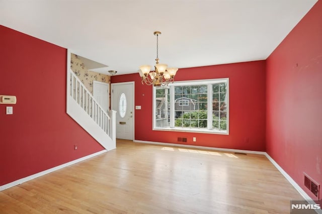 entryway with wood finished floors, visible vents, baseboards, stairs, and a notable chandelier