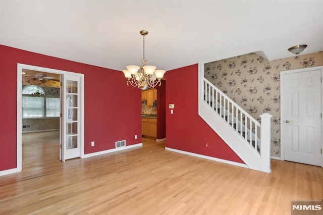 interior space with stairway, baseboards, visible vents, and light wood finished floors