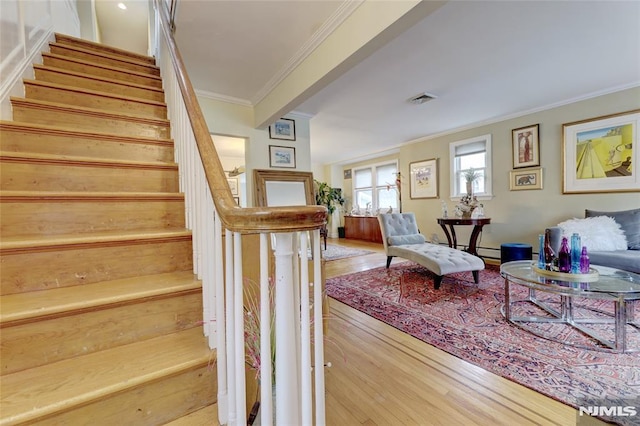 stairs featuring visible vents, crown molding, and wood finished floors