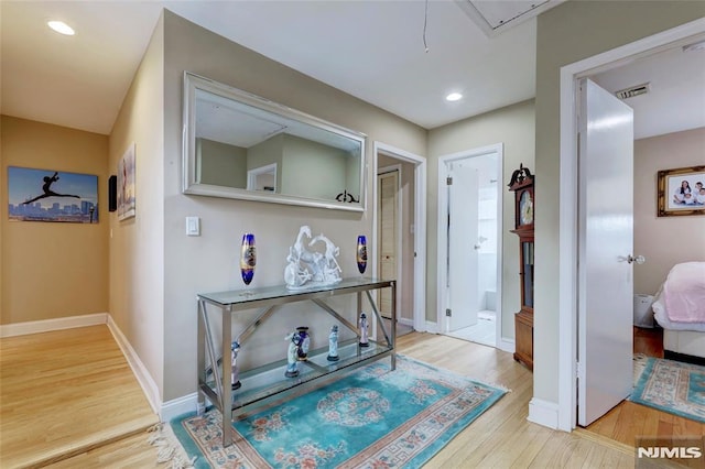 corridor featuring recessed lighting, wood finished floors, visible vents, baseboards, and attic access