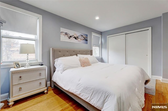 bedroom featuring a closet, baseboards, wood finished floors, and recessed lighting