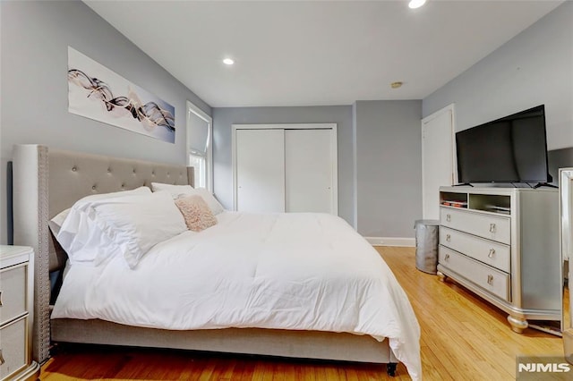 bedroom with light wood-type flooring, baseboards, a closet, and recessed lighting