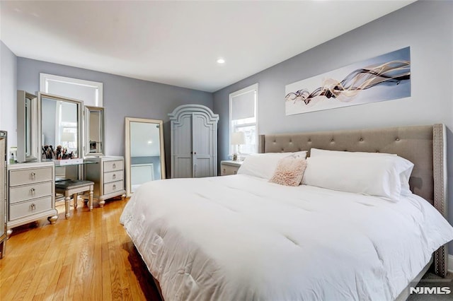 bedroom with multiple windows and light wood-style flooring