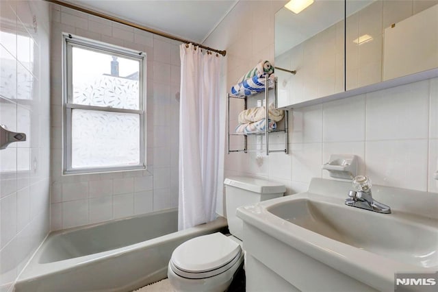 full bathroom with a healthy amount of sunlight, tasteful backsplash, a sink, and tile walls