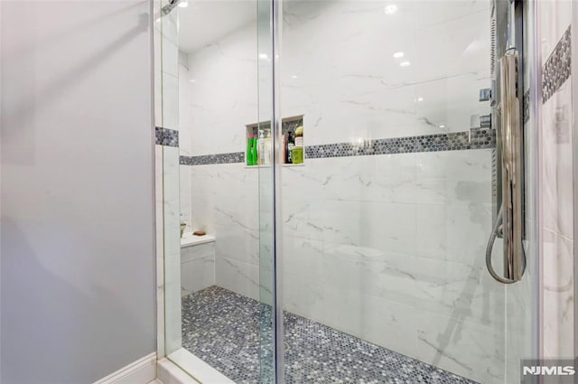 bathroom featuring a shower stall and baseboards